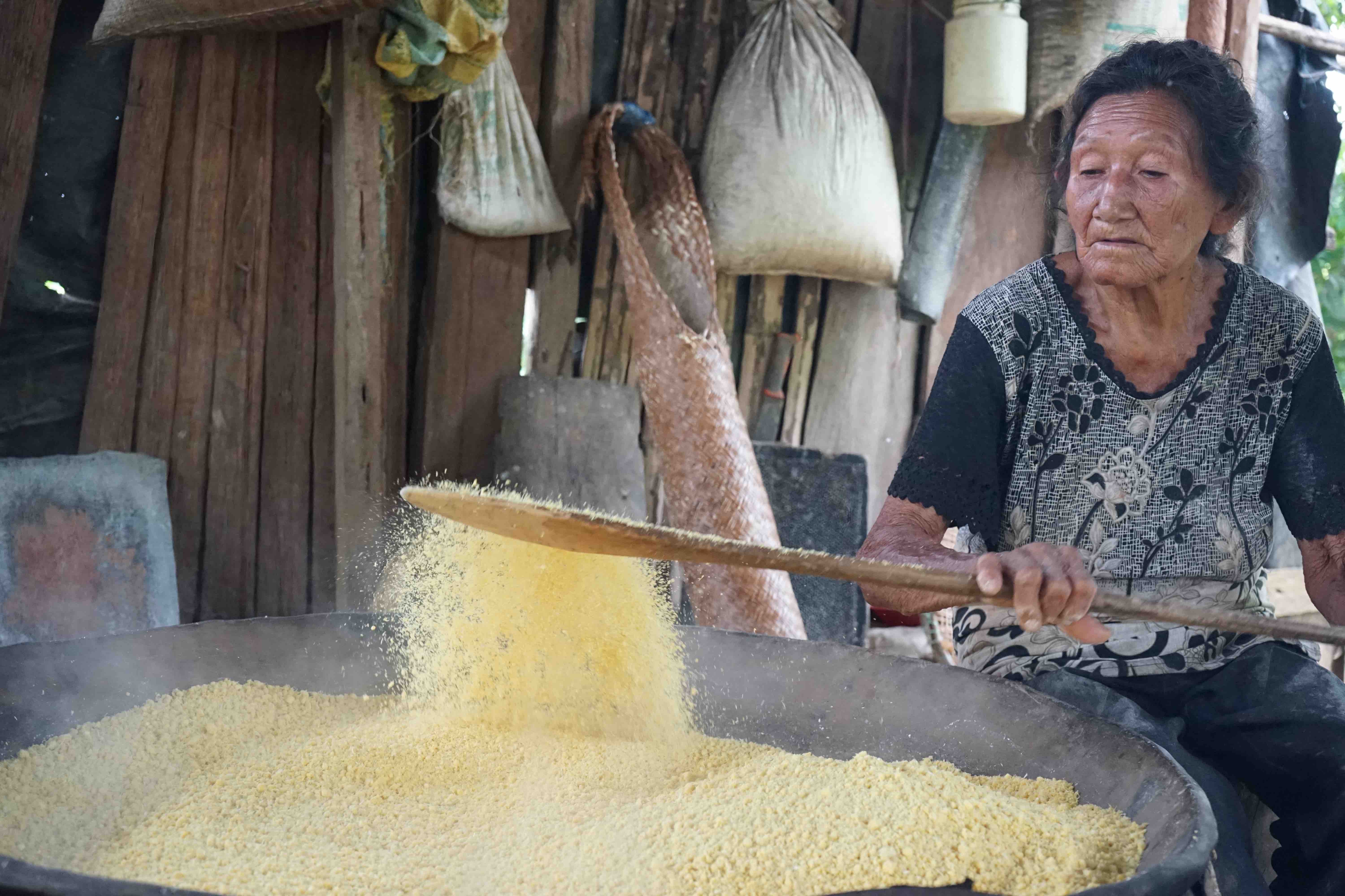 Mujer cocinando fariña de yuca 
